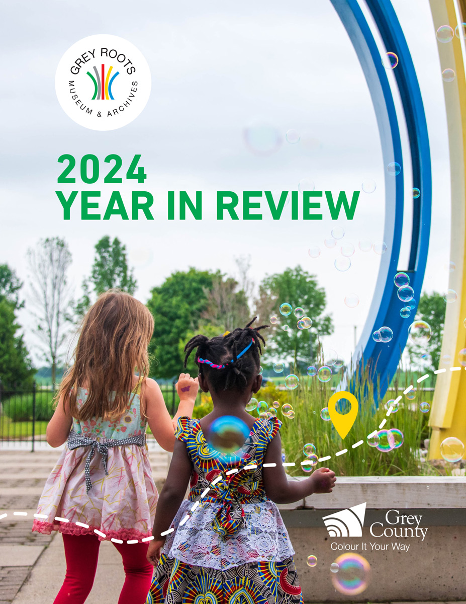 Two children walk toward a large, colorful outdoor sculpture surrounded by floating bubbles. One child wears a dress with red leggings, and the other wears a colorful dress with braided hair. Trees and greenery fill the background. Text on the image reads: “2024 Year in Review,” “Grey Roots Museum & Archives” (with logo), and “Grey County Colour It Your Way” (with logo).
