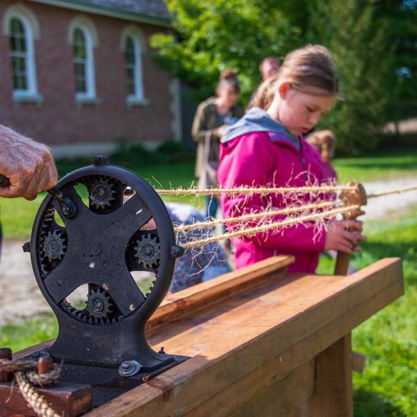 A child using an antique rope making device.